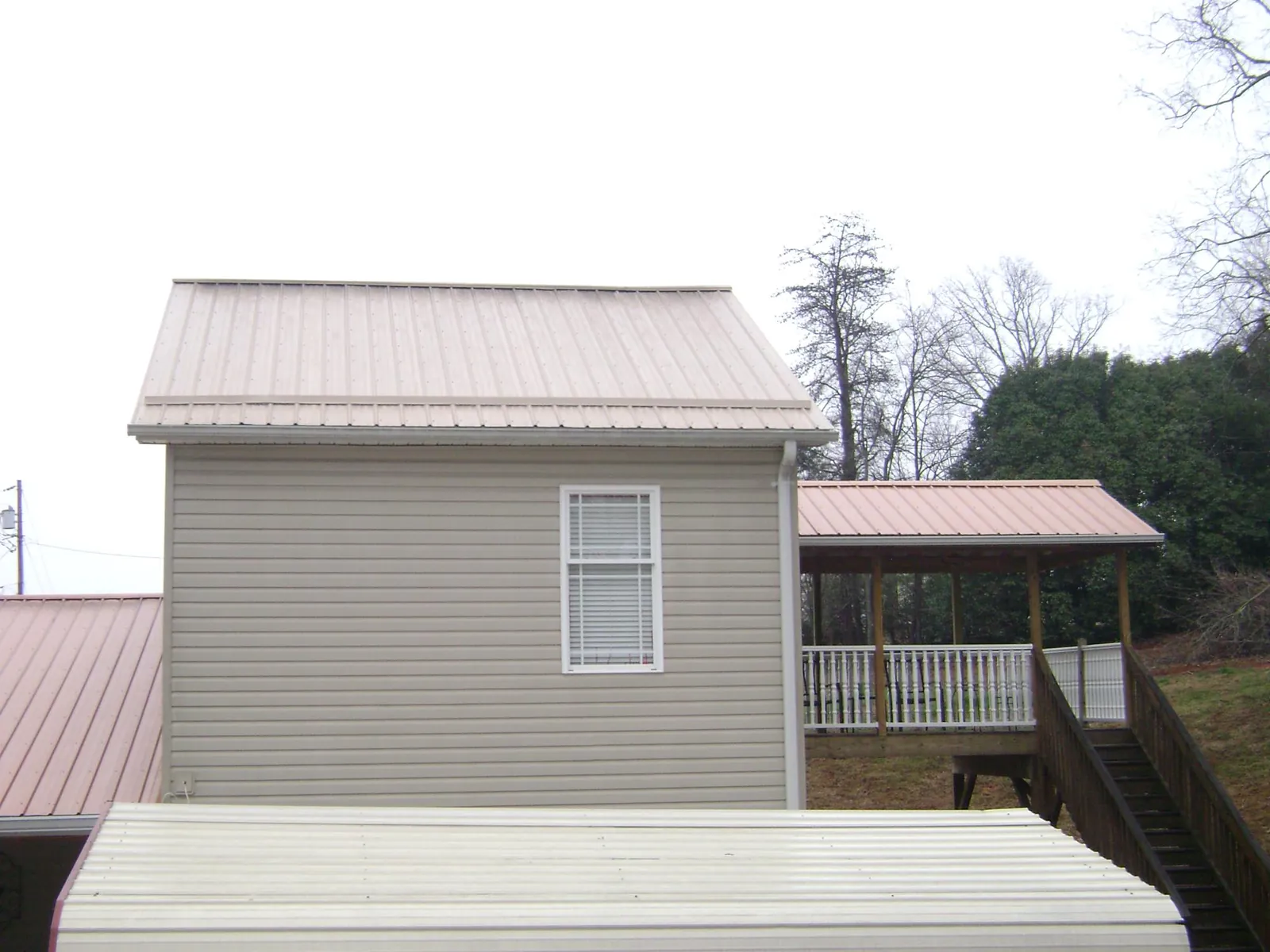 Tan metal roofs on a two story addition and attached porch, from a Roof Replacement job in Waimanalo