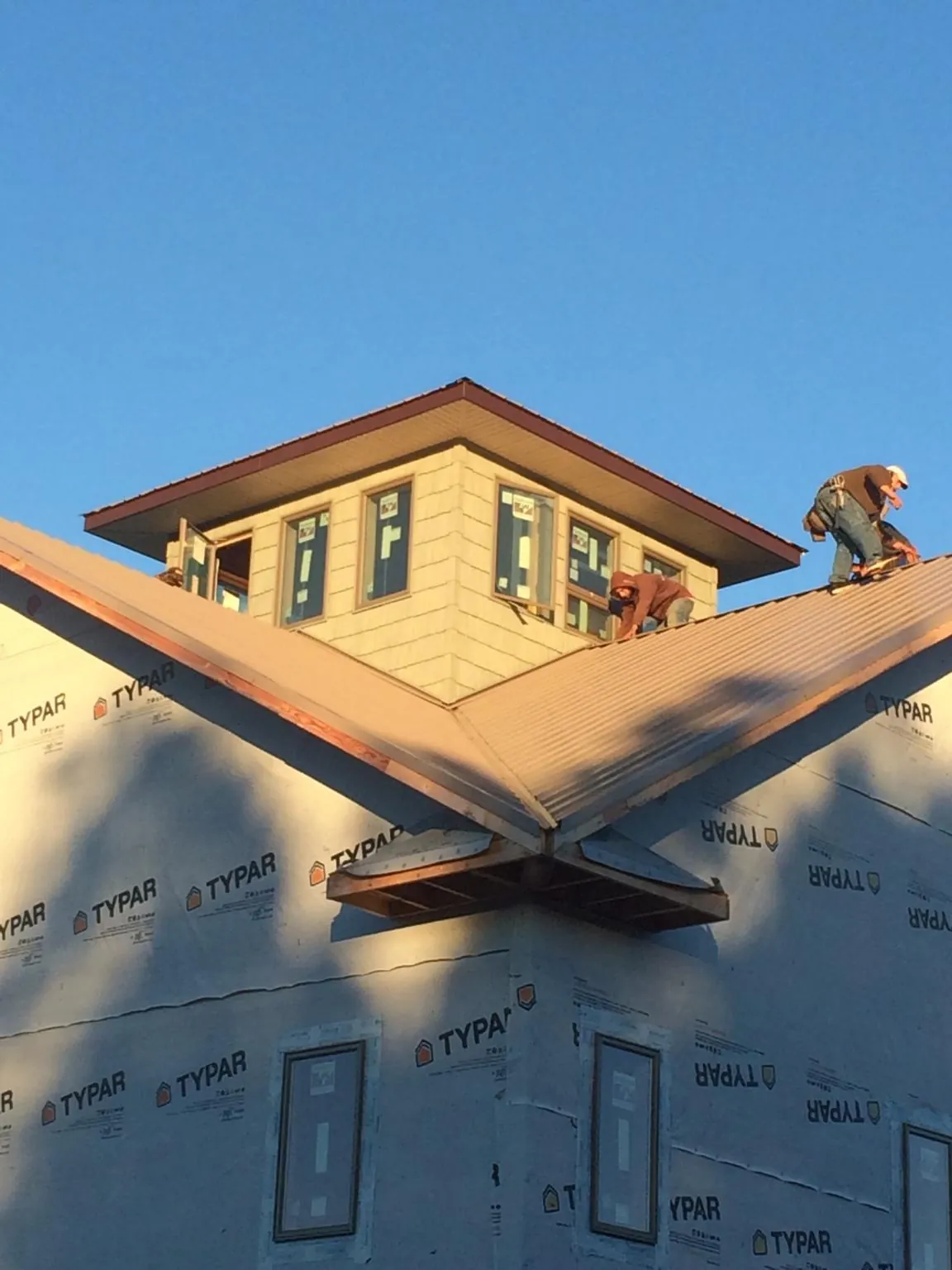 Roofers working around a rooftop cupola on a new metal roof at sunset — Roof Waterproofing in Waimanalo by Roofing Brothers